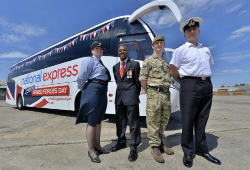 One man dressed in British Army uniform, one in Royal Navy attire, a woman in RAF uniform standing in front of a national express coach. 