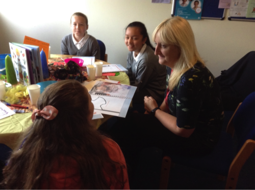 Teacher at students chatting around a table at a school