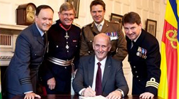 Image that shows a man in a suit signed with all three armed forces presented.